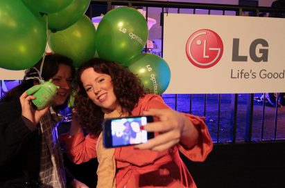 Two attendees take a selfie with an android doll and LG Optimus One balloons, while leaving the event.