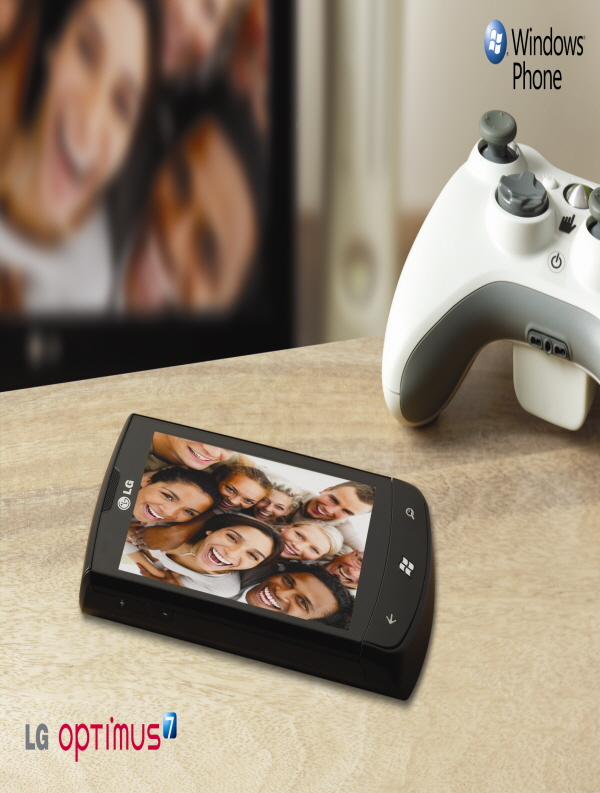 Promo shot of the LG Optimus 7 laid flat on a table next to a Microsoft Xbox 360 controller alongside the ‘Windows Phone’ logo