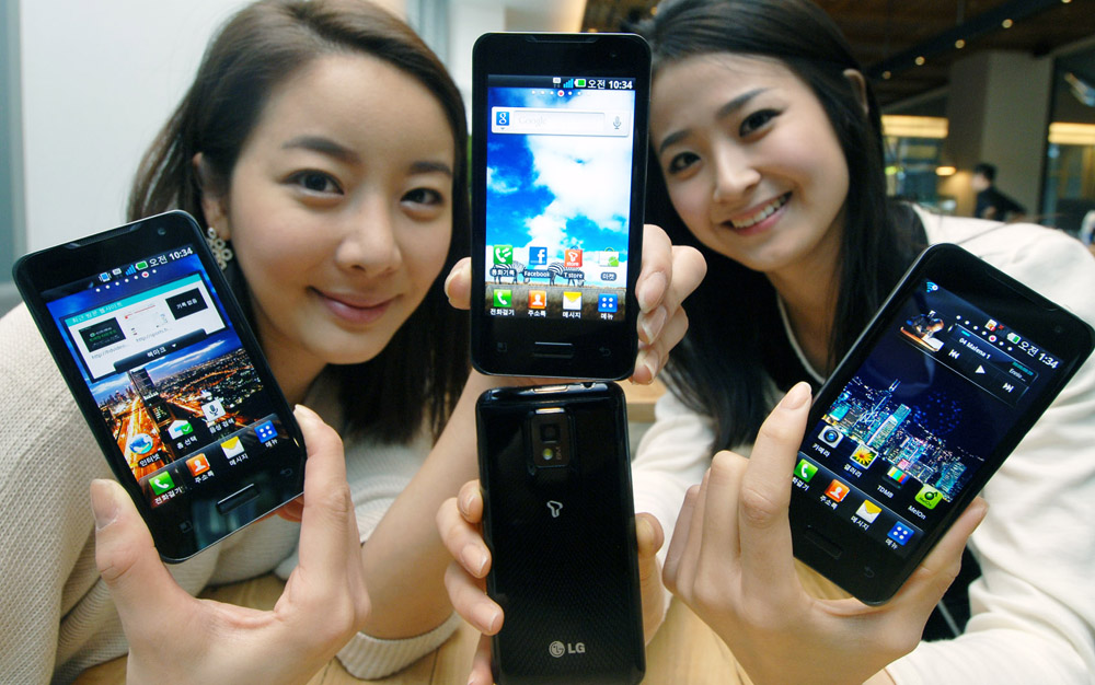 Two models hold up four models of the LG Optimus 2X displaying both its front and back at the smartphone’s launch event.