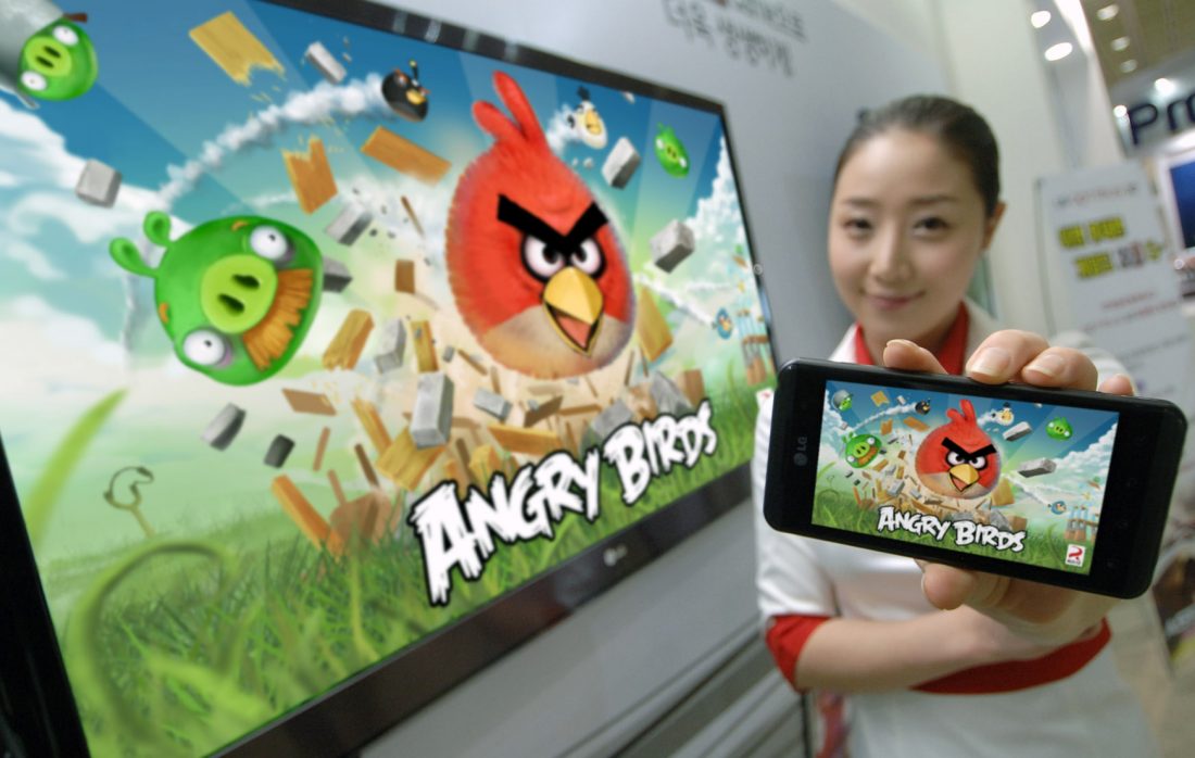 A model holding an OPTIMUS SERIES SMARTPHONE with ANGRY BIRDS RIO on the screen