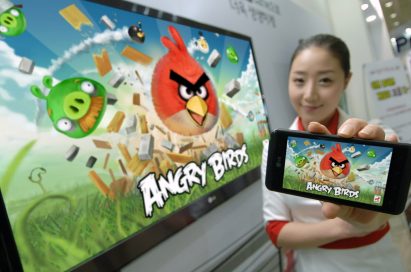 A model holding an OPTIMUS SERIES SMARTPHONE with ANGRY BIRDS RIO on the screen