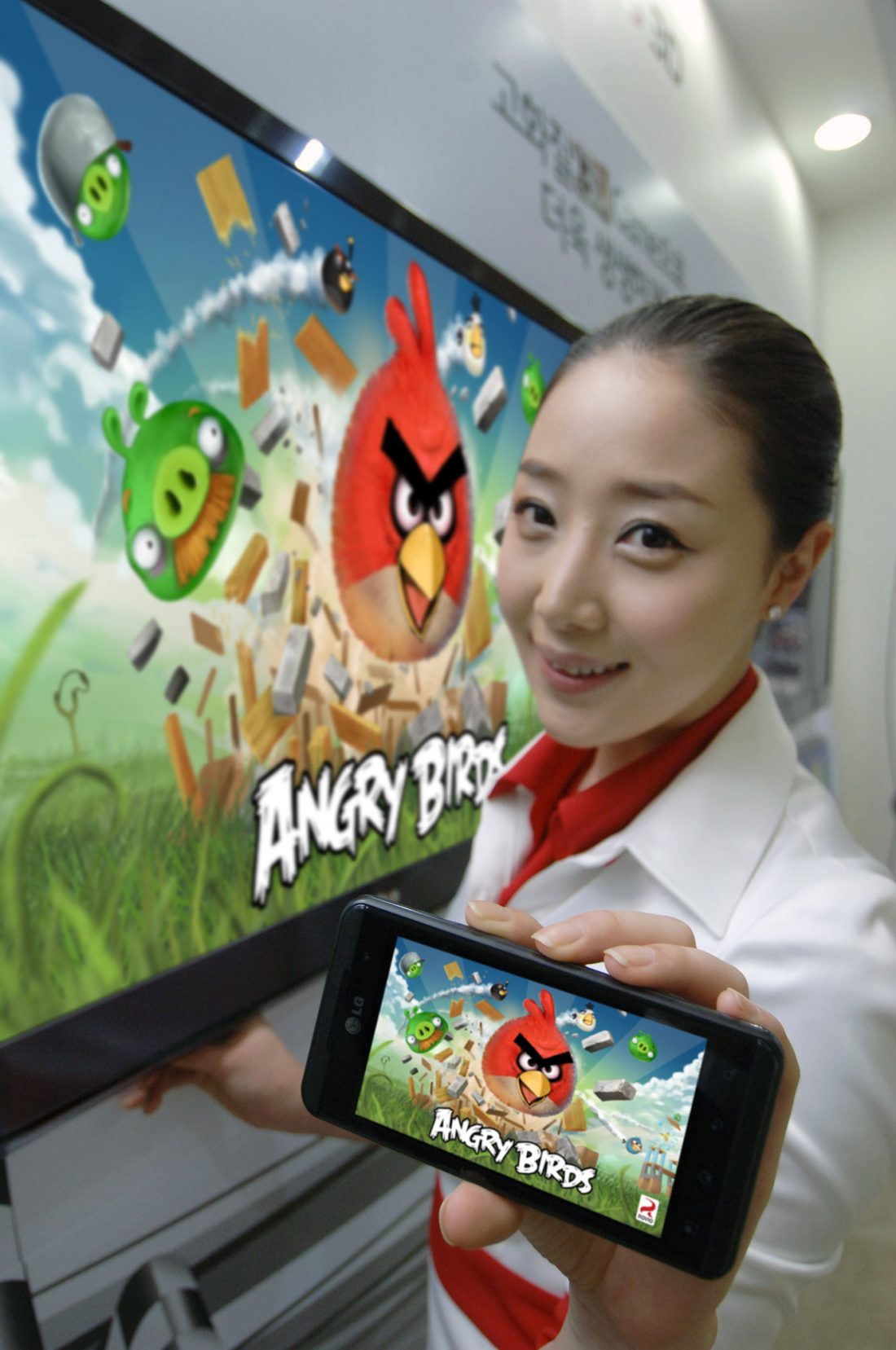 A close view of a model holding an OPTIMUS SERIES SMARTPHONE with ANGRY BIRDS RIO on the screen