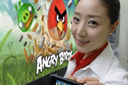 A close view of a model holding an OPTIMUS SERIES SMARTPHONE with ANGRY BIRDS RIO on the screen