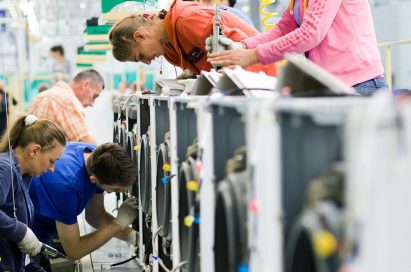 Many factory staff members assemble washing machines at an appliance manufacturing plant in Poland
