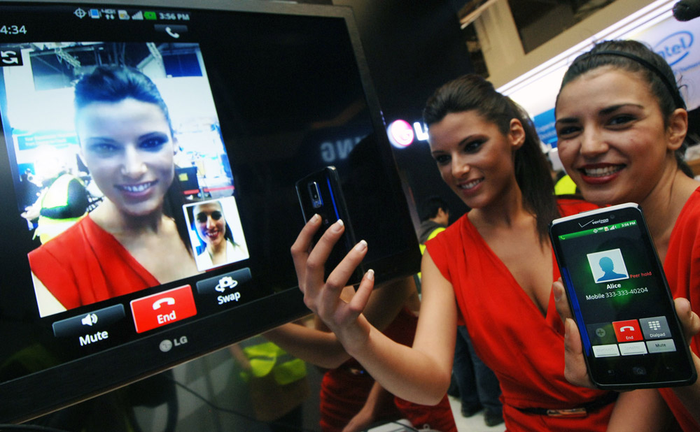 Another view of two models trying out the Voice to Video Convention feature on their LG mobile phones