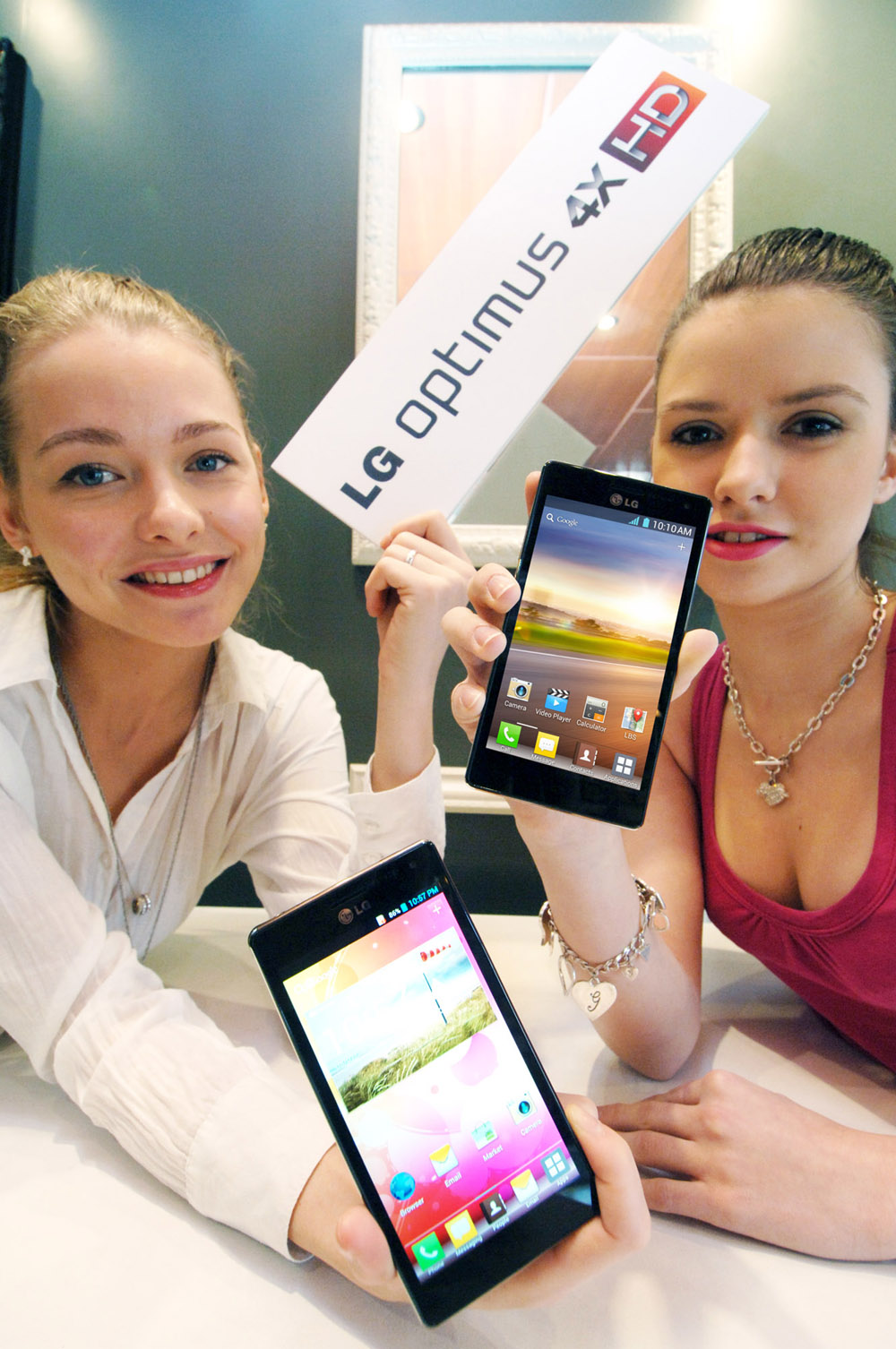 Two models holding up two LG QUAD-CORE smartphones and a promotional panel engraved with the brand name LG OPTMUS 4X HD