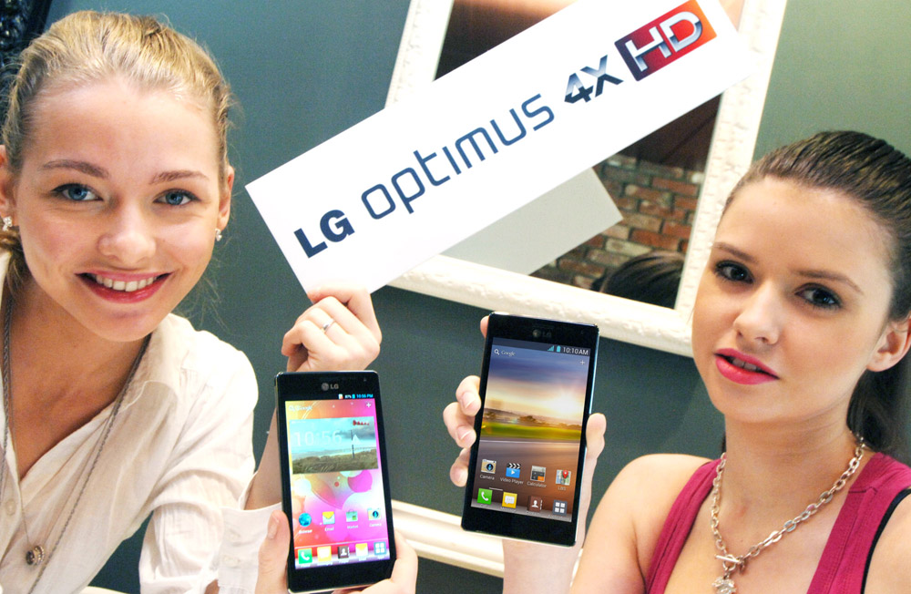 A different-angle photo of two models holding up two LG QUAD-CORE smartphones and a promotional panel engraved with the brand name LG OPTMUS 4X HD