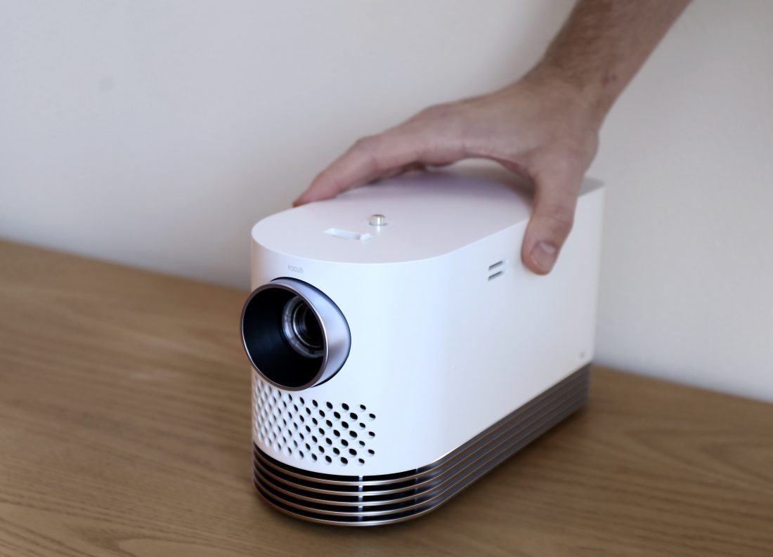 Front view of LG Probeam Laser Projector (model HF80J) facing 15 degrees to the left while being touched by a man's hand
