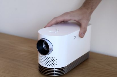 Front view of LG Probeam Laser Projector (model HF80J) facing 15 degrees to the left while being touched by a man's hand