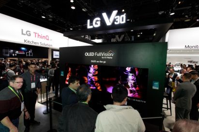 LG staff members speak with visitors in front of the LG V30’s CES display which boasts LG’s OLED FullVision TVs too