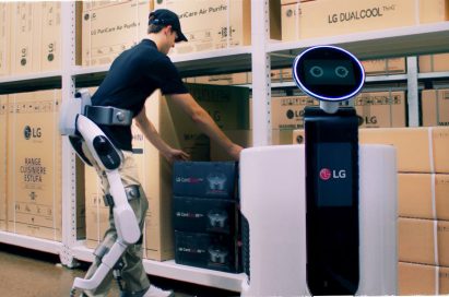 Man wearing LG CLOi SuitBot to move a box to the LG Shopping Cart Robot in a LG warehouse