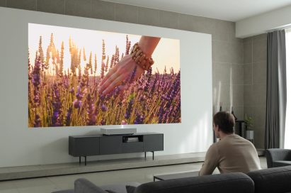 A man is watching a vivid image displayed by the LG CineBeam Laser 4K projector model HU85L