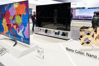 Two LG 8K NanoCell LCD TV models that are positioned the front and the back next to a rotating 8K promotional sign board